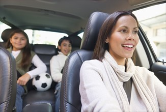 Mother with son (12-13) and daughter (10-11) in car .