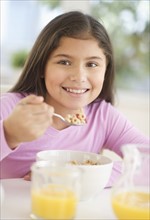 Girl (10-11) having cereals for breakfast.