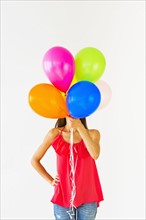 Smiling woman holding balloons, studio shot.