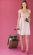Studio shot of woman holding suitcase.
