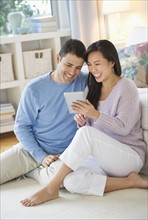 Couple using digital tablet at home.