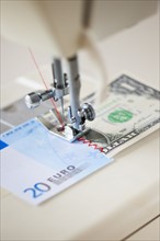 Halves of banknotes being sewed with sewing machine.