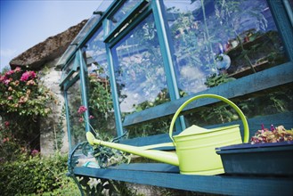 Ireland, County Westmeath, Watering can in front of greenhouse. Photo : Jamie Grill