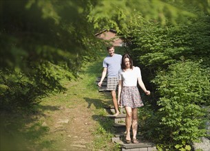 USA, New York, Putnam Valley, Roaring Brook Lake, Couple walking down steps among trees. Photo:
