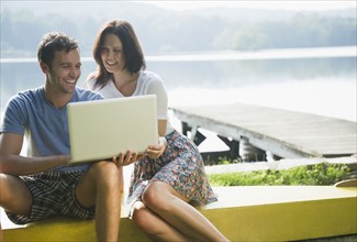 Roaring Brook Lake, Couple using laptop by lake. Photo : Jamie Grill