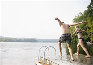 USA, New York, Putnam Valley, Roaring Brook Lake, Couple about to jump from pier to lake. Photo: