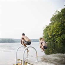 USA, New York, Putnam Valley, Roaring Brook Lake, Couple jumping from pier to lake. Photo : Jamie