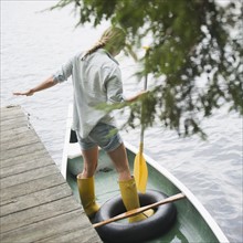 Roaring Brook Lake, Woman standing in boat with paddle. Photo : Jamie Grill