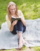 Woman reading book in park. Photo : Daniel Grill