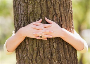 Close up of woman's hands embracing tree. Photo : Daniel Grill