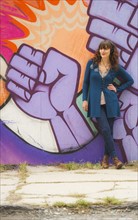 Woman standing against wall with graffiti. Photo: Daniel Grill