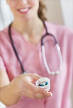 Close up of female nurse holding cup with pills. Photo : Daniel Grill