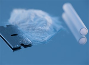 Close up of cocaine and blow tube on blue background. Photo : Daniel Grill