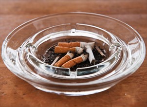 Close up of cigarette butts in glass ashtray. Photo : Daniel Grill