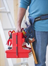 Close up of construction worker carrying tool box. Photo: Daniel Grill