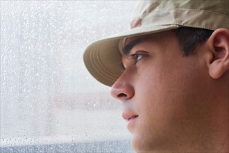 Man wearing military uniform looking through window. Photo : Daniel Grill