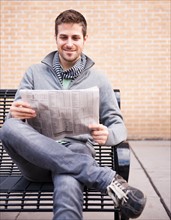 Man on bench reading newspaper. Photo : Daniel Grill