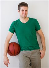 Young man standing with basket ball . Photo : Daniel Grill