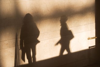 Shadow of two female pedestrians on sunlit wall. Photo: fotog