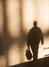Shadow of male pedestrian on sunlit wall. Photo : fotog