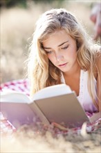 Teenage girl (16-17) reading book outdoors. Photo : Take A Pix Media