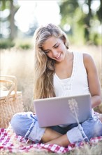 Teenage girl (16-17) using laptop outdoors. Photo: Take A Pix Media