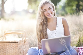 Teenage girl (16-17) posing with laptop outdoors. Photo : Take A Pix Media