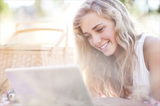 Happy teenage girl (16-17) using laptop outdoors. Photo : Take A Pix Media