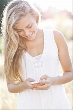 Teenage girl (16-17) text messaging outdoors. Photo : Take A Pix Media