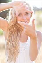 Teenage girl (16-17) displaying finger frame. Photo : Take A Pix Media