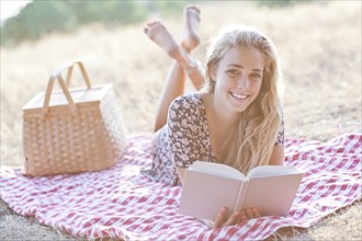 Happy teenage girl (16-17) reading book outdoors. Photo : Take A Pix Media