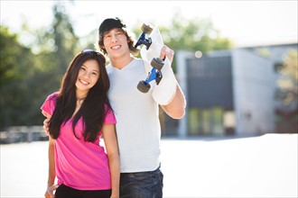Young multi-racial couple posing with skateboard. Photo: Take A Pix Media