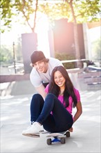 Young multi-racial couple playing with skateboard. Photo : Take A Pix Media