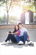 Young multi-racial couple posing with skateboard. Photo : Take A Pix Media