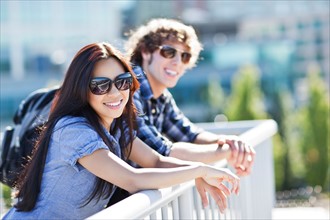 Couple standing by banister outdoors. Photo : Take A Pix Media