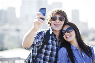 USA, Washington, Seattle, Couple wearing sunglasses photographing themselves with smart phone.