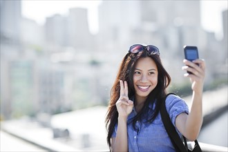 USA, Washington, Seattle, Woman photographing herself with smart phone outdoors. Photo : Take A Pix