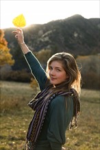 USA, Colorado, Portrait of young woman holding up leaf. Photo : John Kelly