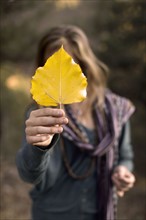 Woman holding leaf in front of face. Photo: John Kelly