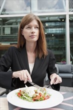 The Netherlands, Amsterdam, Portrait of businesswoman eating salad in cafe. Photo : Jan Scherders