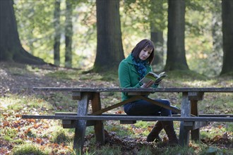 The Netherlands, Veluwezoom, Posbank, Woman reading book in park. Photo : Jan Scherders