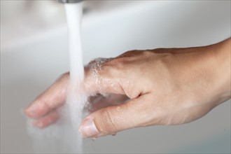 Woman's hand under tap pouring water. Photo : Jan Scherders