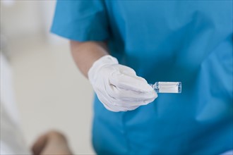 Midsection of surgeon holding vial. Photo: db2stock