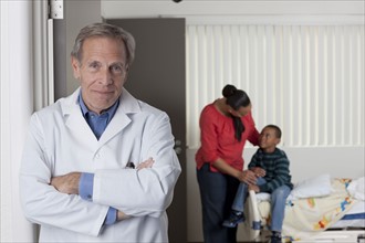 Portrait of male doctor with patients in background. Photo : db2stock
