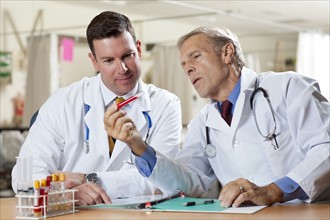 Two doctors examining test tube in hospital. Photo : db2stock