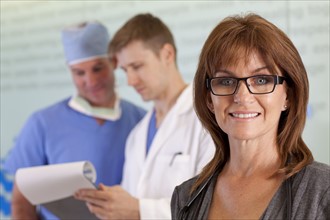 Portrait of female doctor, male doctor and surgeon in background. Photo : db2stock