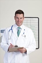 Portrait of male doctor holding clipboard. Photo : db2stock