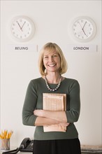 Portrait of businesswoman with world clocks behind. Photo : Rob Lewine