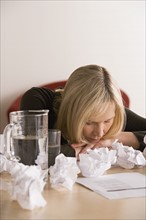 Businesswoman sleeping at desk with crumpled paper balls. Photo: Rob Lewine