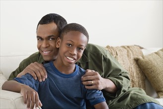 Portrait of Father and Son (12-13) sitting on sofa. Photo : Rob Lewine